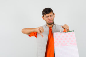 Homem desapontado segurando sacola de compras, representando erros que fazem você perder vendas ao anunciar um imóvel.