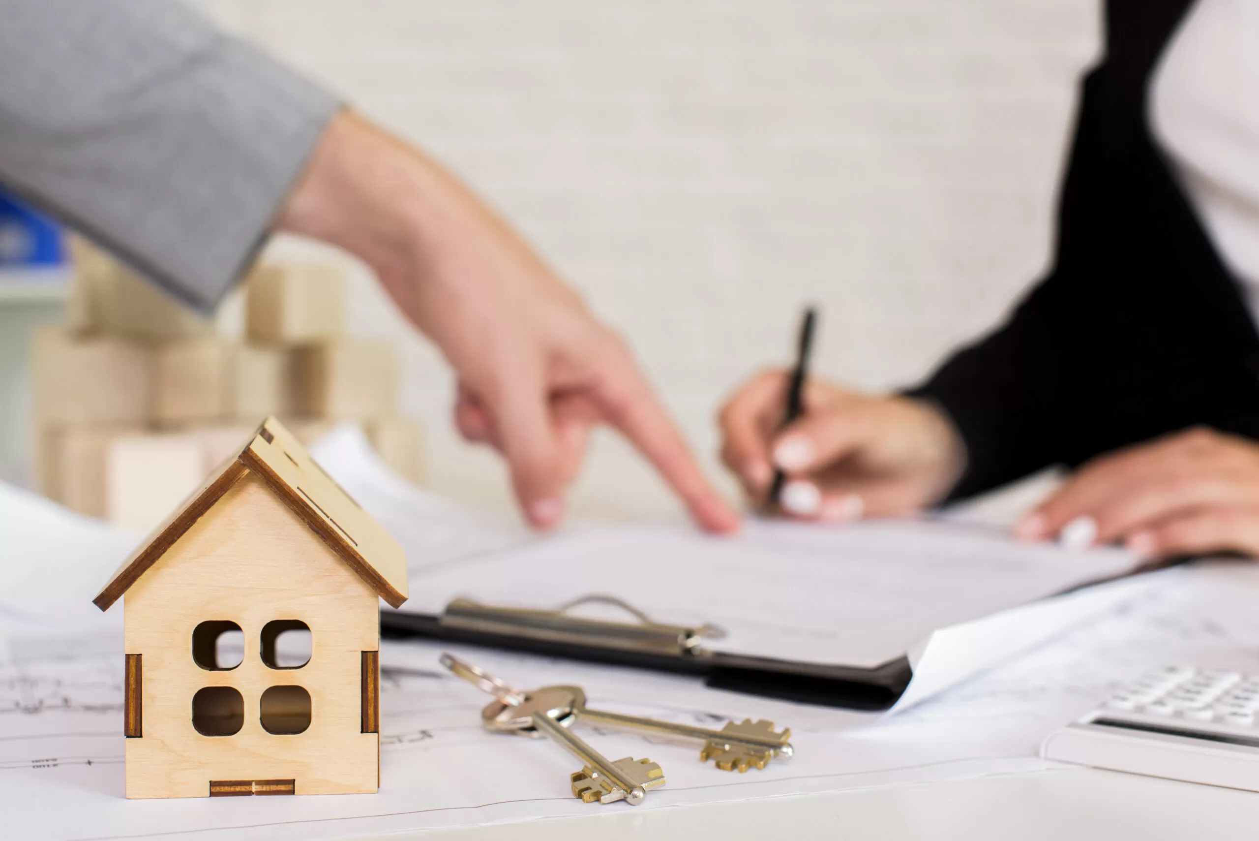 Obrigações das Imobiliárias na Lei do Inquilinato: Contrato de locação sendo assinado, com miniatura de casa e chaves em destaque, representando a importância da conformidade legal na administração de imóveis.